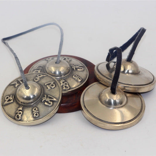 Ringvale – Two engraved bells and two plain polished bells joined by leather cords, resting on a round wooden stand